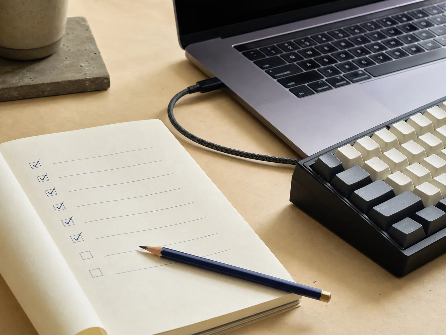 Paper verification checklist beside a connected laptop and mechanical keyboard.